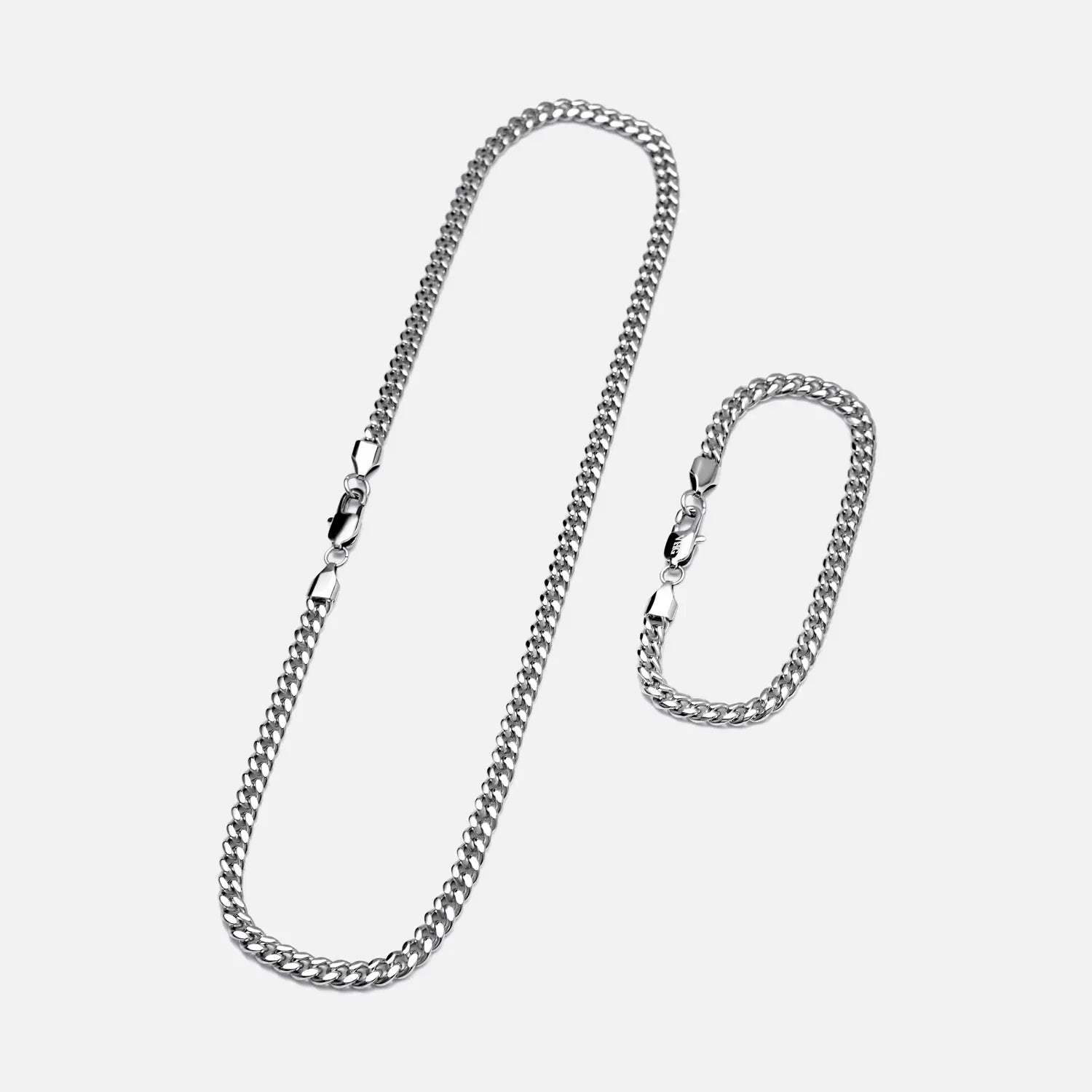Cuban Link Halskette und Cuban Link Armband in 4mm breite aus Edelstahl nebeneinander liegend auf einem weißen Hintergrund