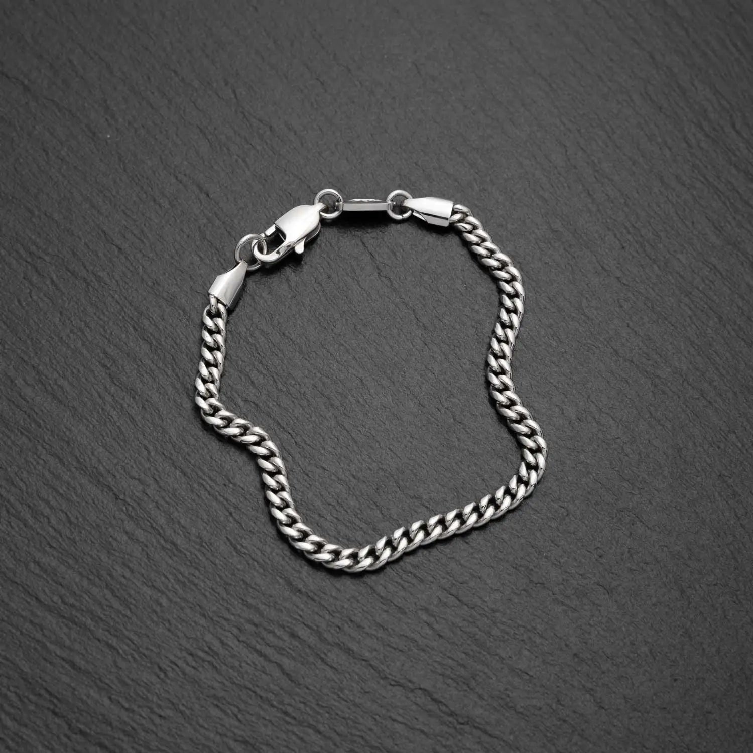 Herren Cuban Link Panzerarmband in 4mm breite aus Edelstahl auf einem schwarzen rauen Hintergrund