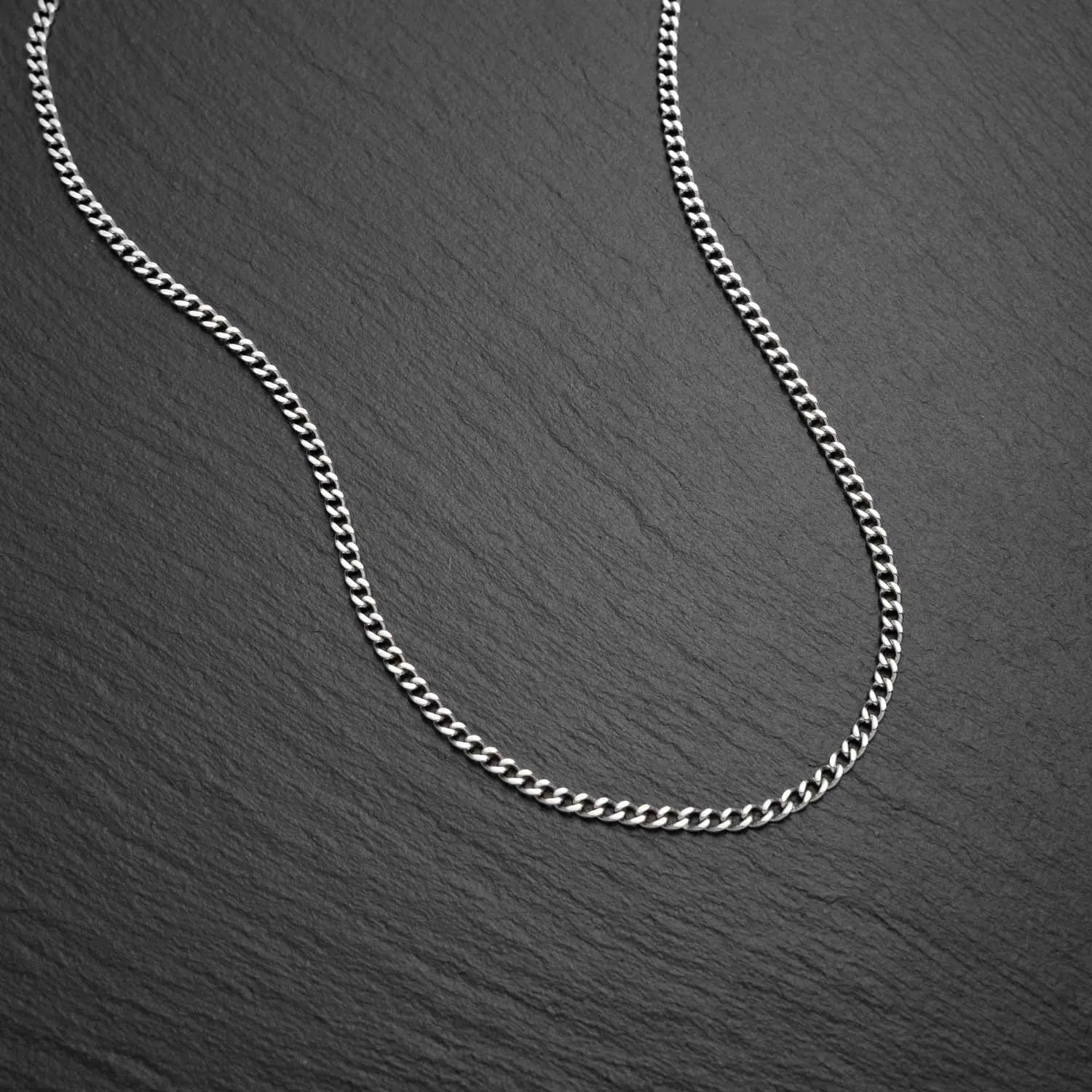 Herren Cuban Link Panzerhalskette mit 2mm breiten Gliedern auf einem schwarzen Hintergrund mit rauer Struktur