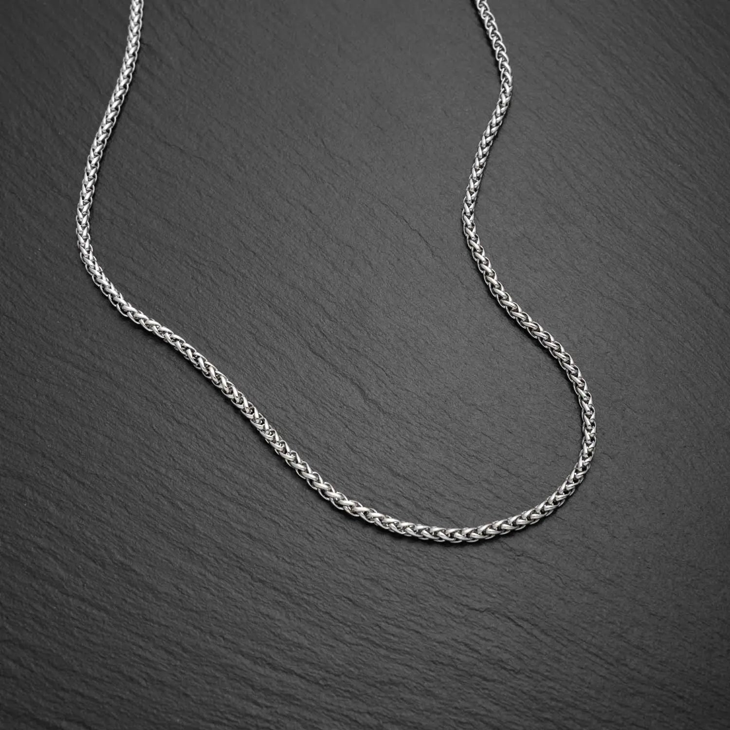 Herren Wheat Halskette in 3mm breite aus Edelstahl auf einem schwarzen rauen Hintergrund